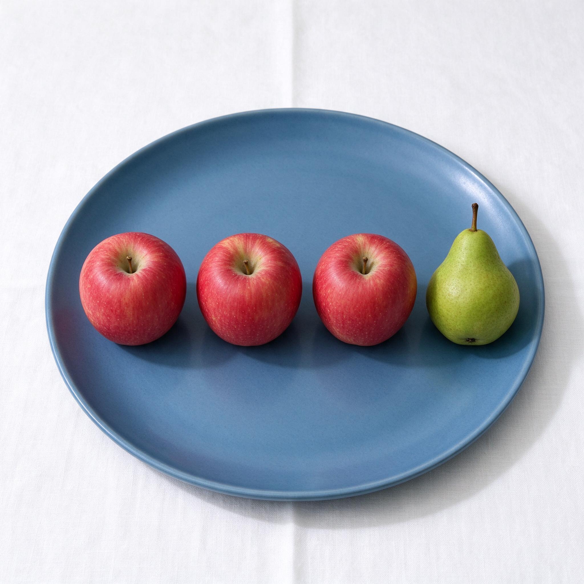 Seedream 5.0 Flash: Three red apples and one green pear arranged in a single row on a blue plate, top-down view, white tablecloth