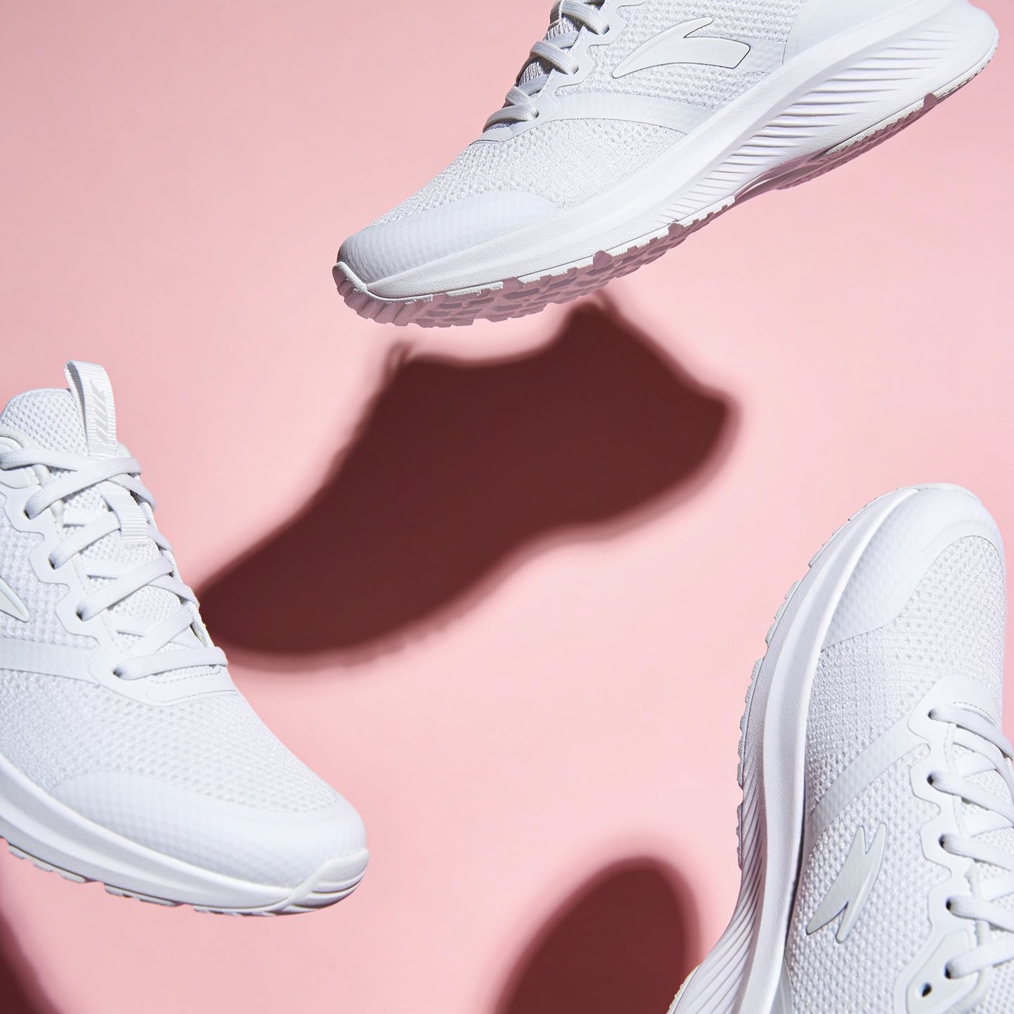 Seedream 4.5: A pair of white running shoes floating mid-air over a pastel pink background, even studio lighting, catalogue shot