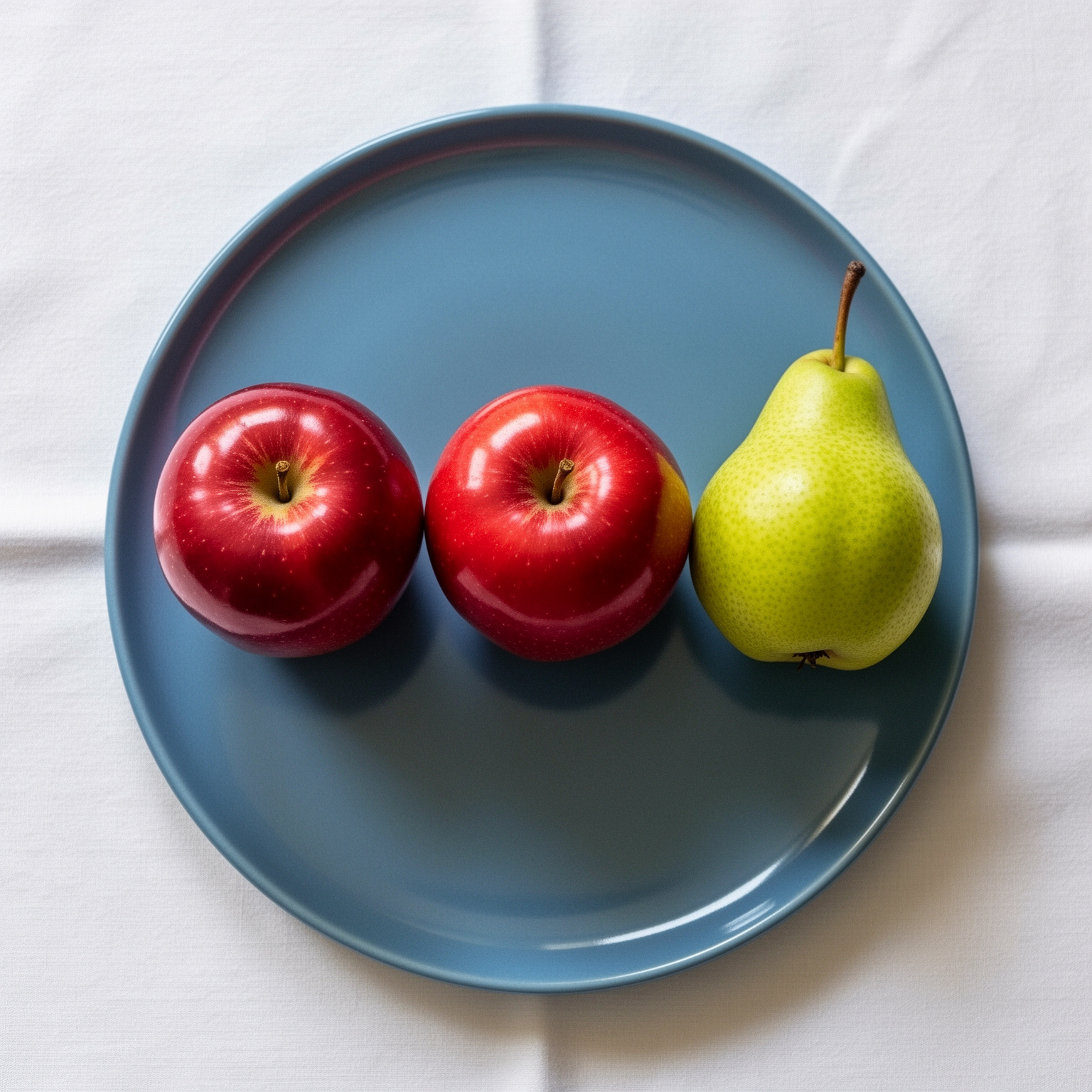 FLUX.2: Three red apples and one green pear arranged in a single row on a blue plate, top-down view, white tablecloth