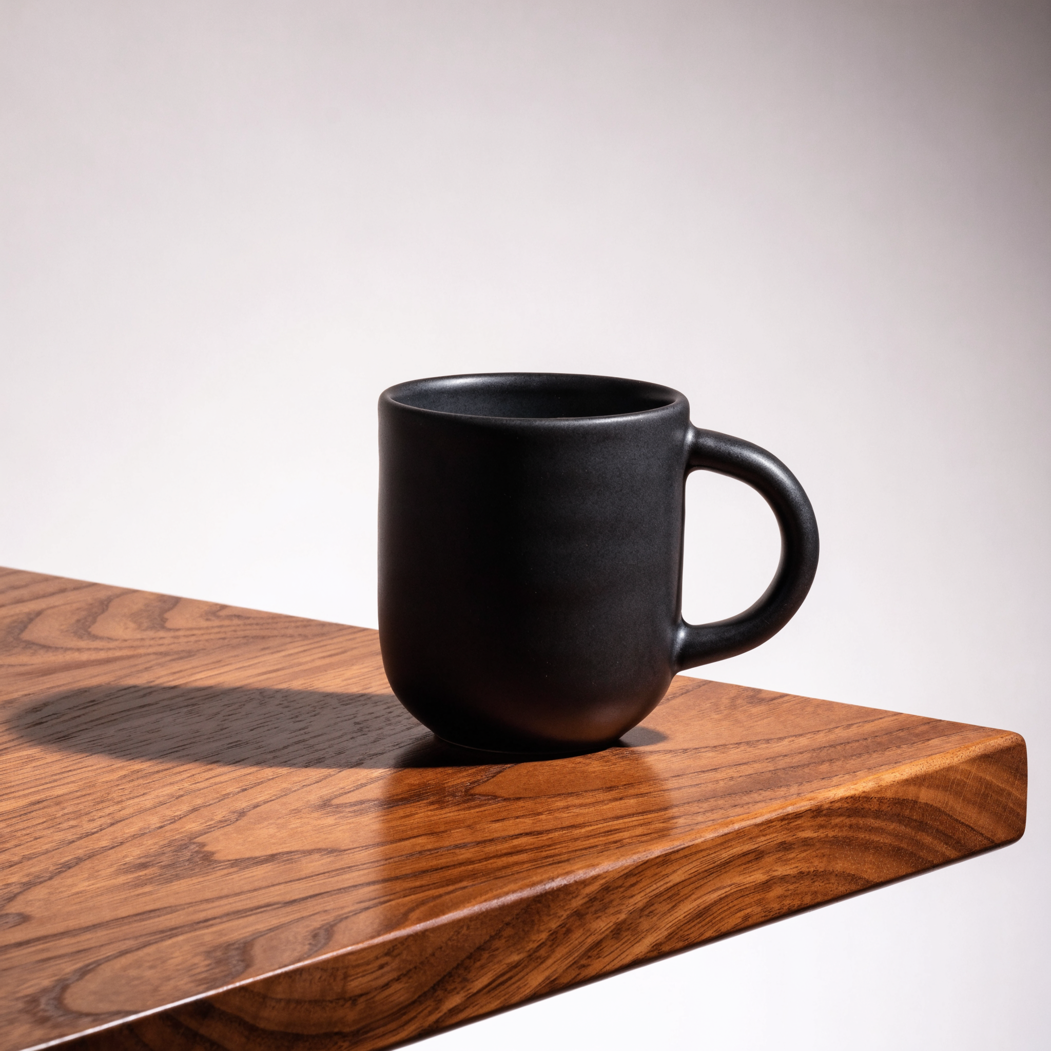 Recraft V4.1 Pro: A matte black ceramic coffee mug on a walnut table, single soft light from the left, minimal studio backdrop, product photography